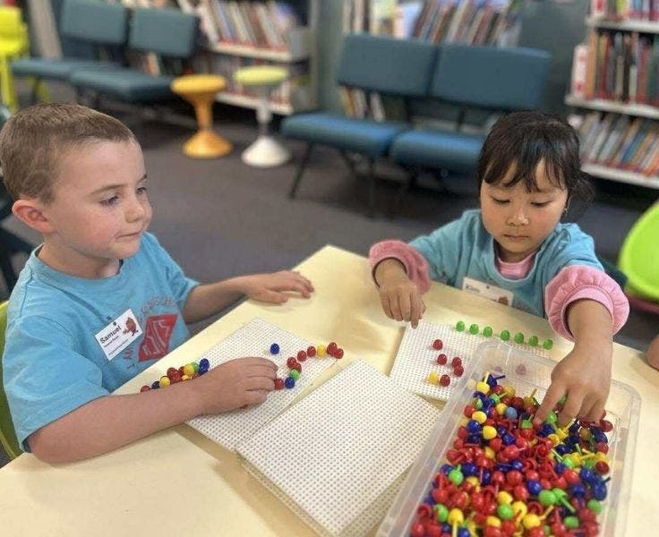 two students at a desk playing with pegboard